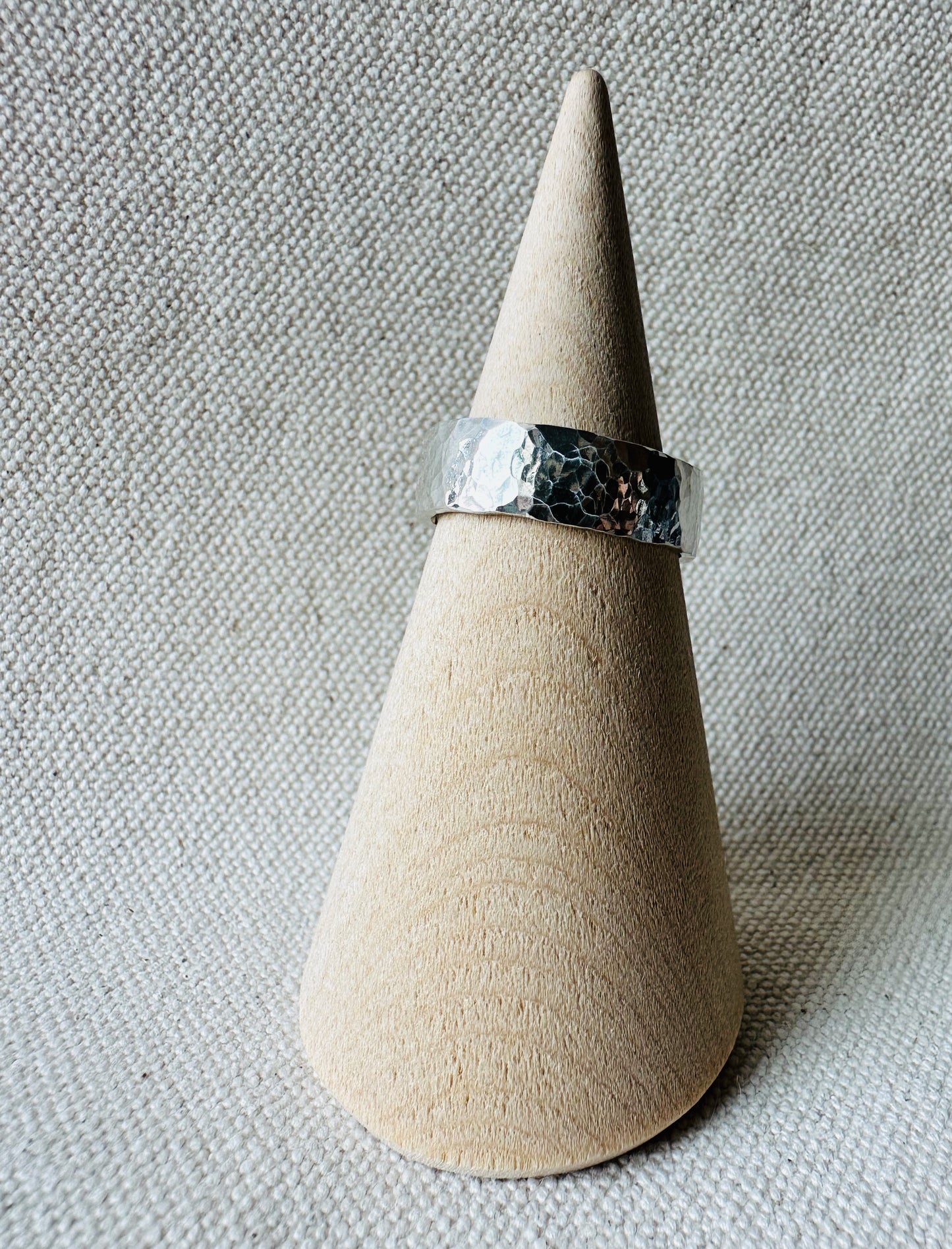 Hammered thick band silver ring on wooden ring holder. 