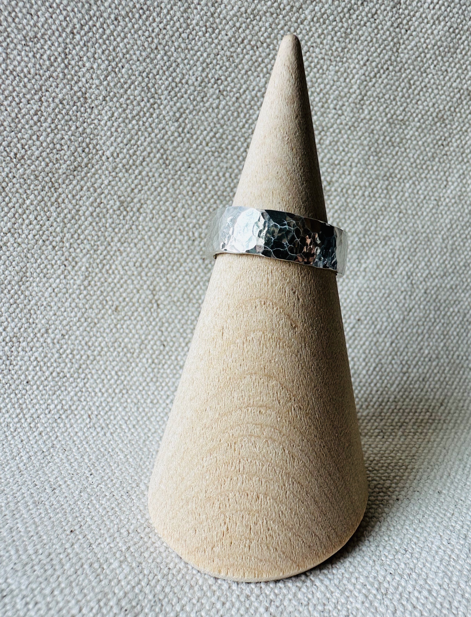 Hammered thick band silver ring on wooden ring holder. 