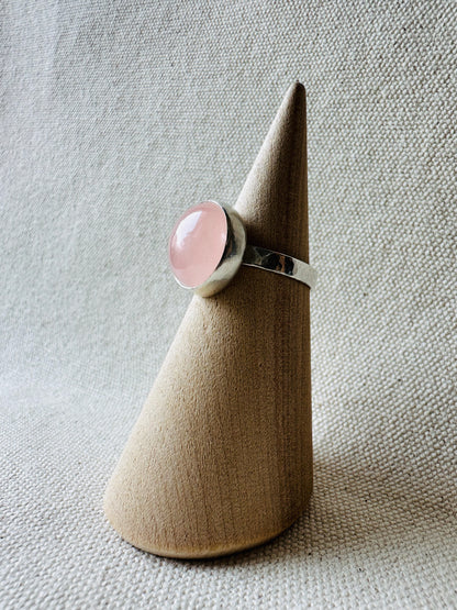 Silver rose quartz gemstone ring with hammered ring band on wooden ring holder.  