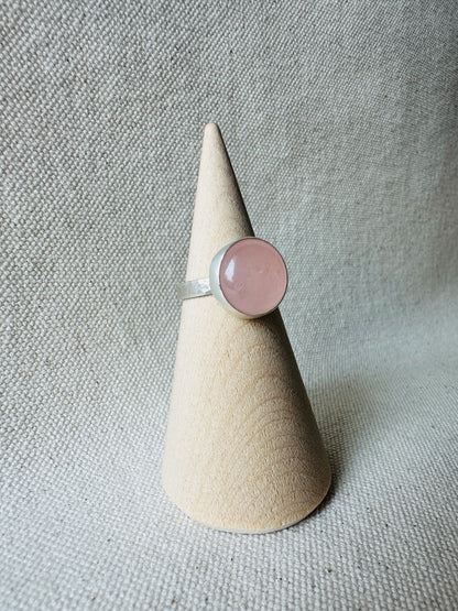 Silver rose quartz gemstone ring with hammered ring band on wooden ring holder.  