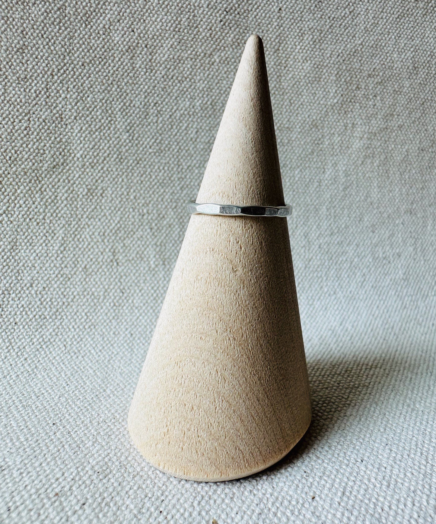 Hammered geometric silver ring on wooden ring holder. 