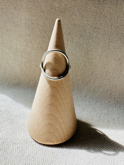 Open circle silver ring with satin finish on a wooden ring holder. 