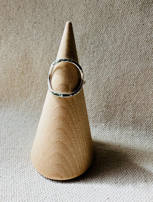 Open circle silver ring with hammered finish on a wooden ring holder. 