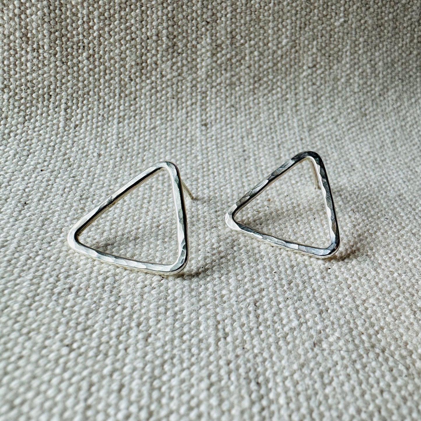 Close-up image of silver hammered triangle stud earrings, approximate size (2 cm).