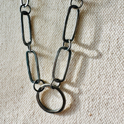 Close up image of hand fabricated, oxidized sterling silver, single circle and 6 paperclip link chain necklace.