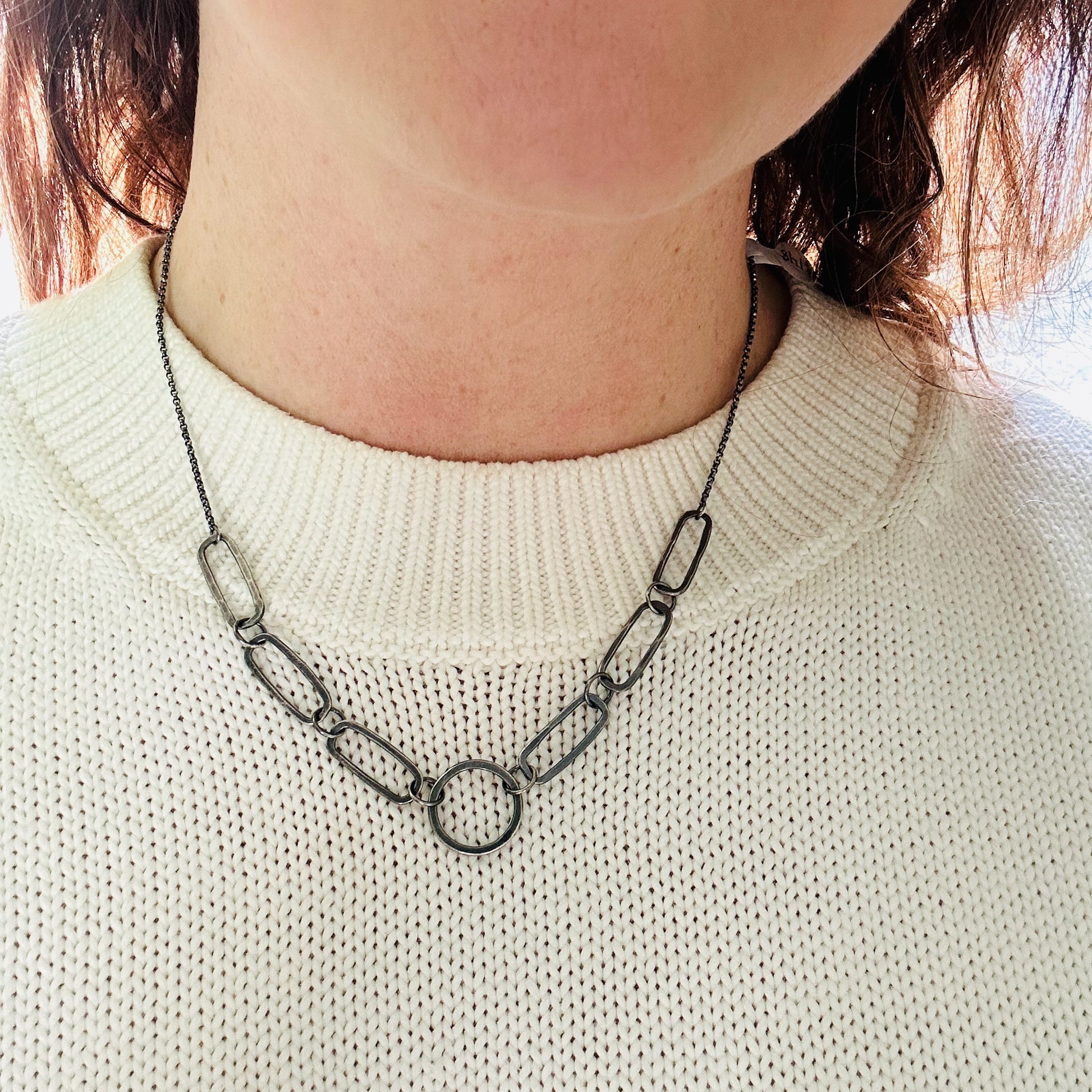 Image of hand fabricated, oxidized sterling silver, single circle and 6 paperclip link chain necklace being worn. 