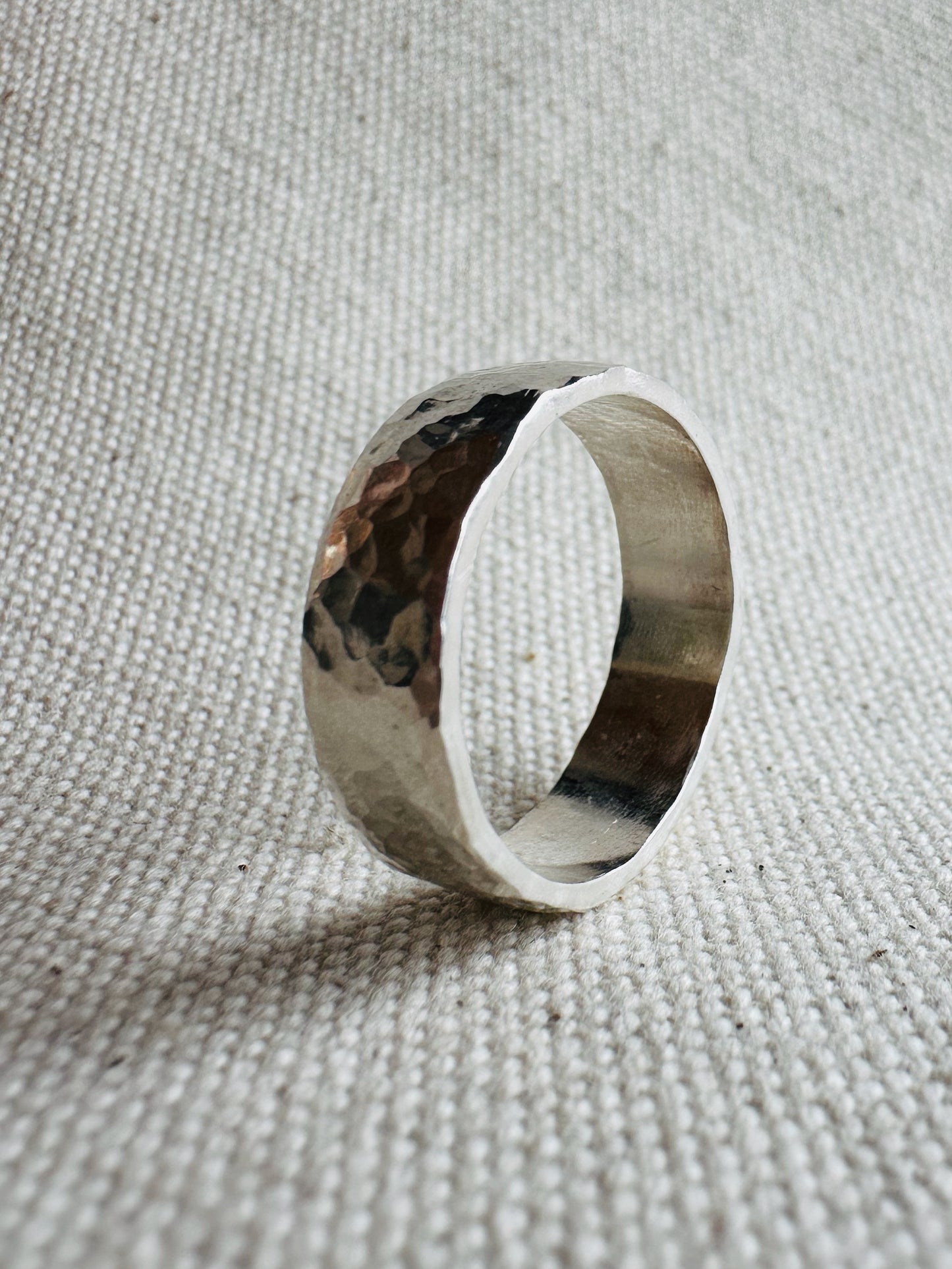 Hammered thick band silver ring standing on side. 