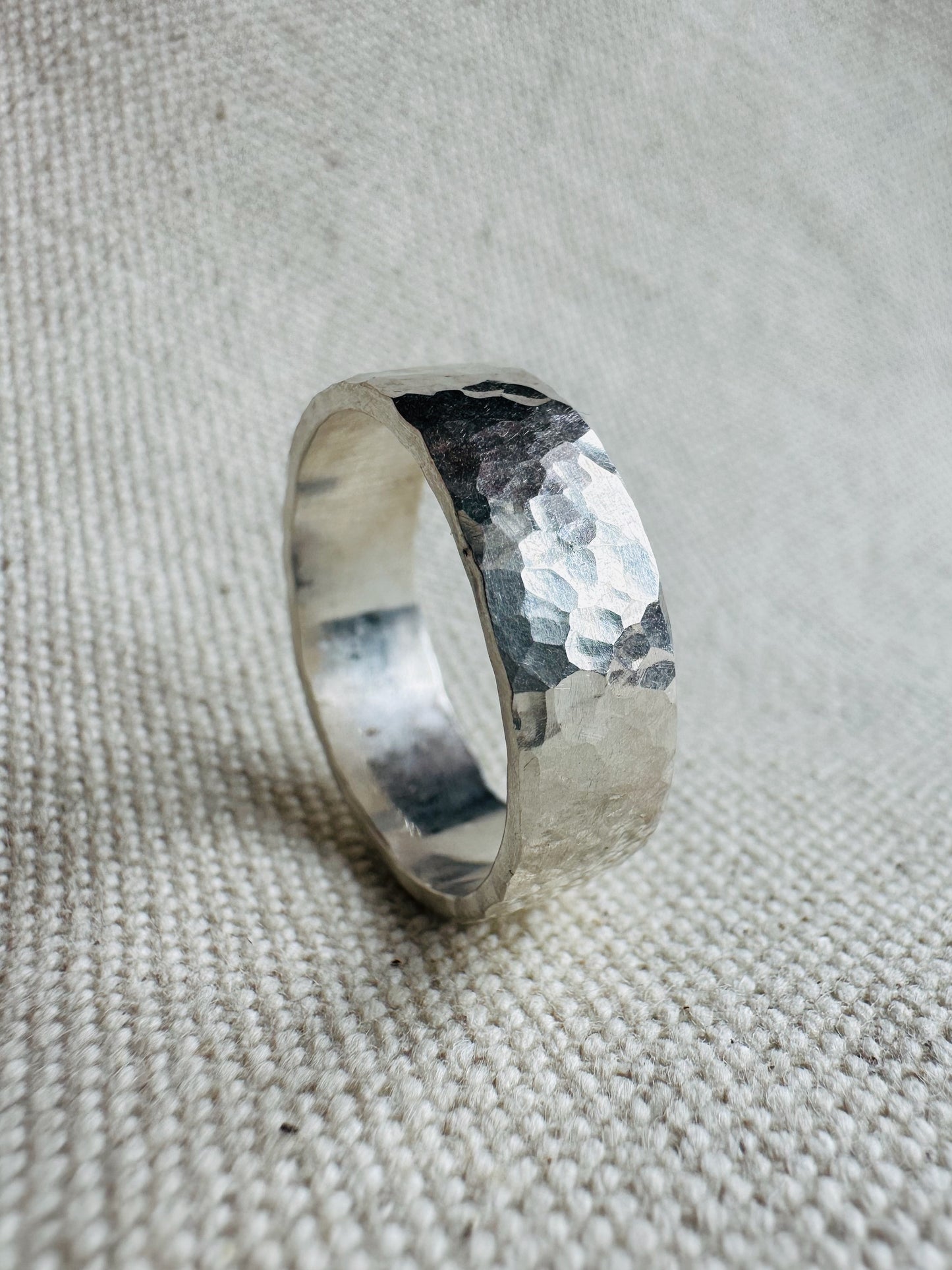 Hammered thick band silver ring standing on side. 