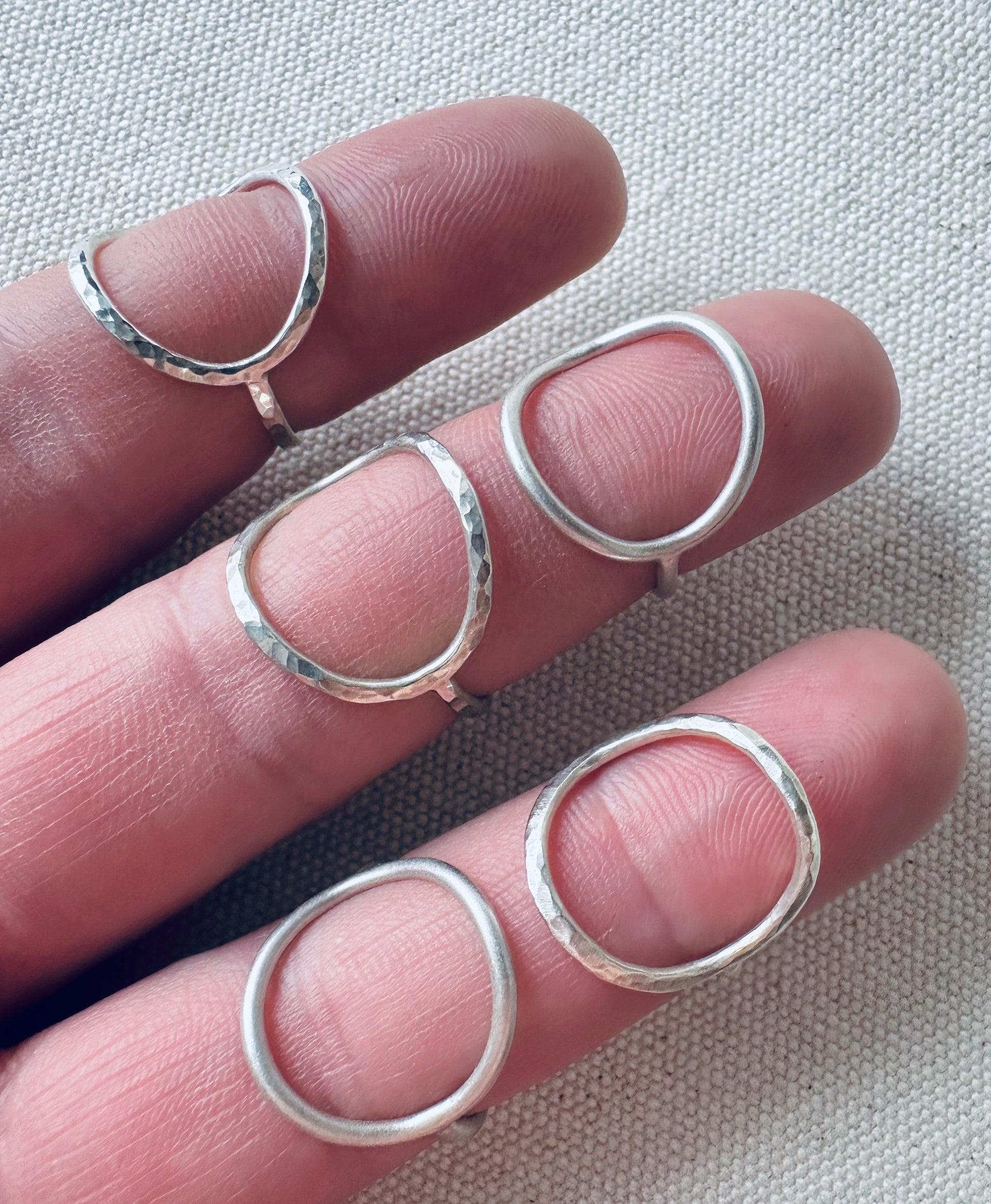 Open circle silver rings shown on fingers. 