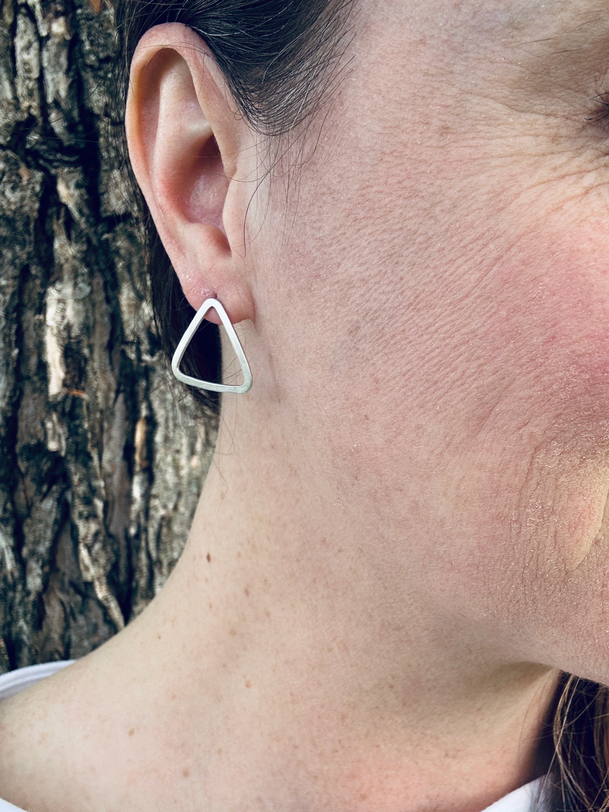 Sterling silver satin triangle stud earrings being worn, showing approximate size (2 cm).