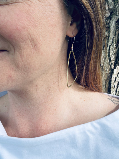 Brass wing shaped dangle earrings being worn, showing approximate size (5 cm plus ear wire length).