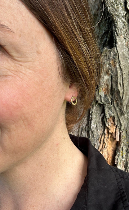 Brass satin circle stud earrings being worn, showing approximate size (1 cm).