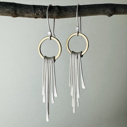 Pair of brass circle dangle earrings with silver fringe and silver ear wires with satin finish.