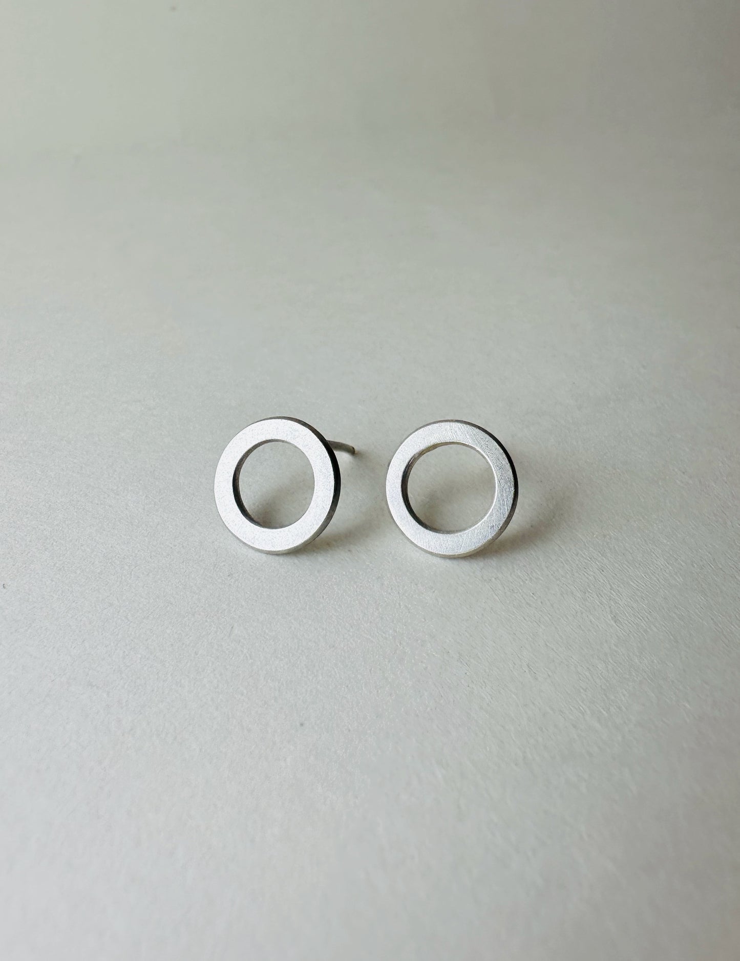 Pair of silver circle earrings on a light gray background
