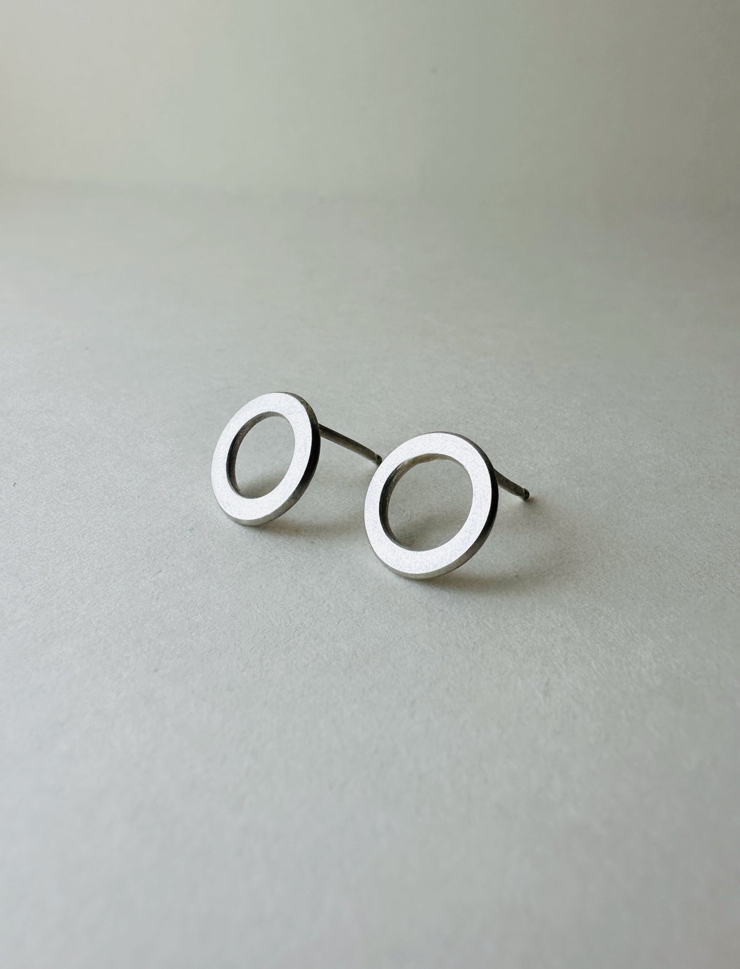 Pair of silver circle earrings on a light gray background