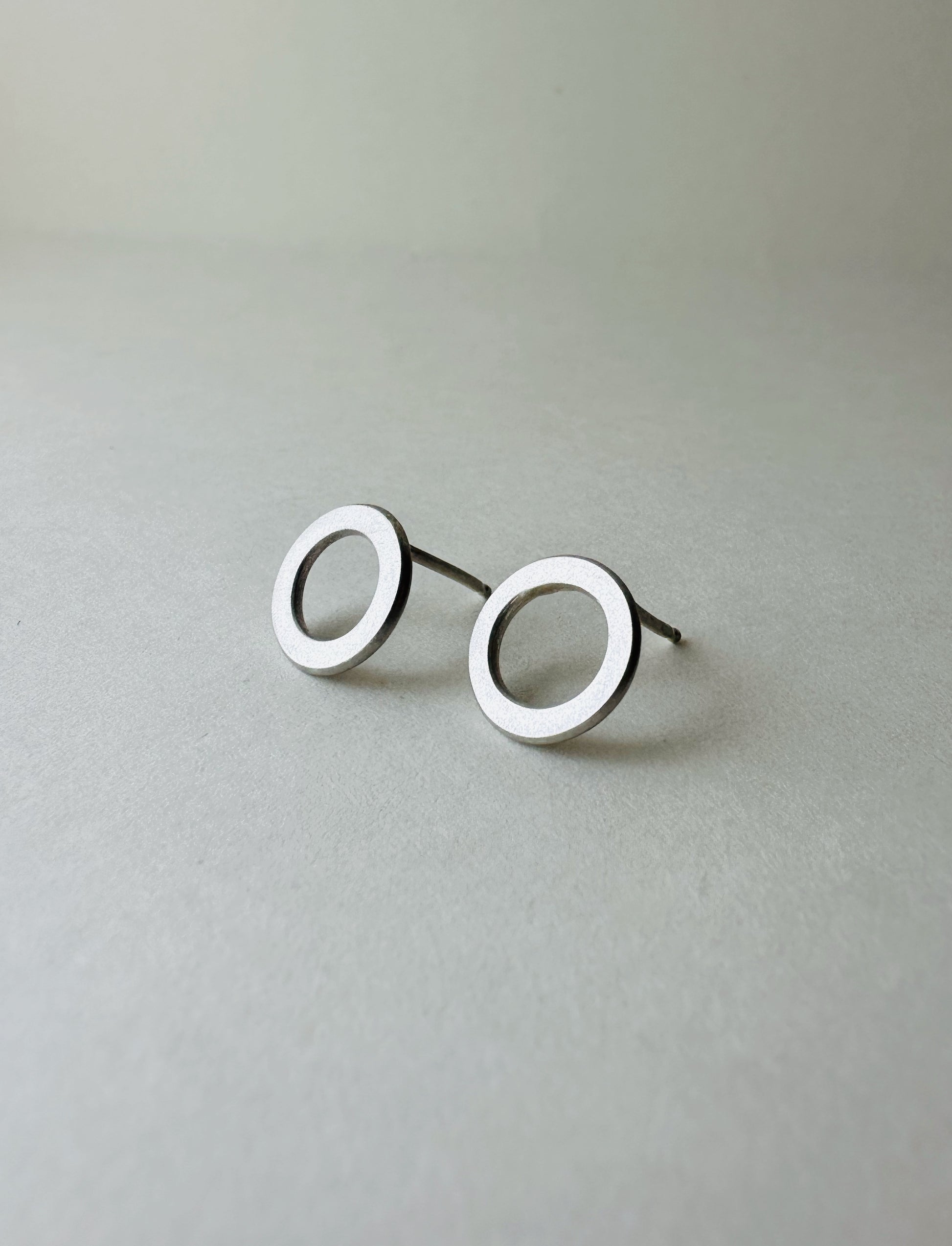 Pair of silver circle earrings on a light gray background